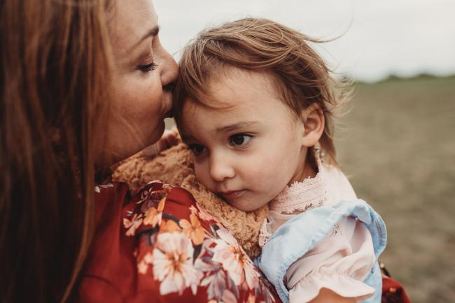 Mother kissing her daughter's forehead with Perth family photographer at Perry's Paddock