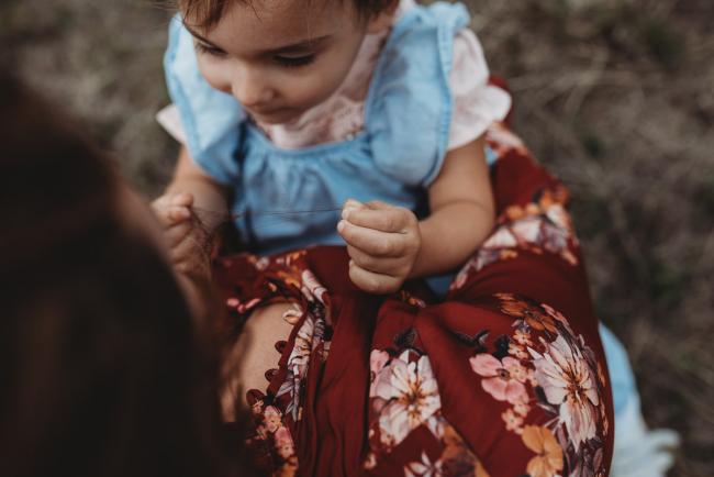 little girl sitting on the lap of her mother and playing with her hair with Perth family photographer at Perry's Paddock