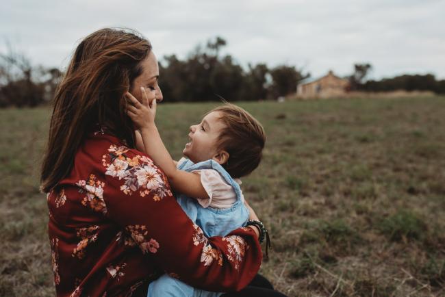 little girl sitting on her mothers lap and squeezing her cheeks with Perth family photographer at Perry's Paddock