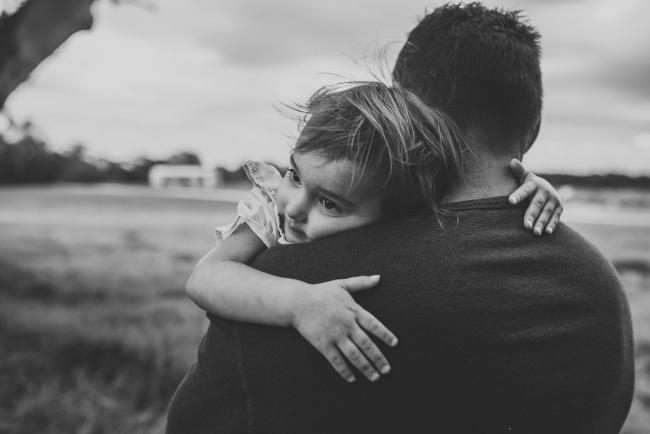 Black and white image of little girl cuddling her father and resting on his shoulder with Perth family photographer at Perry's Paddock