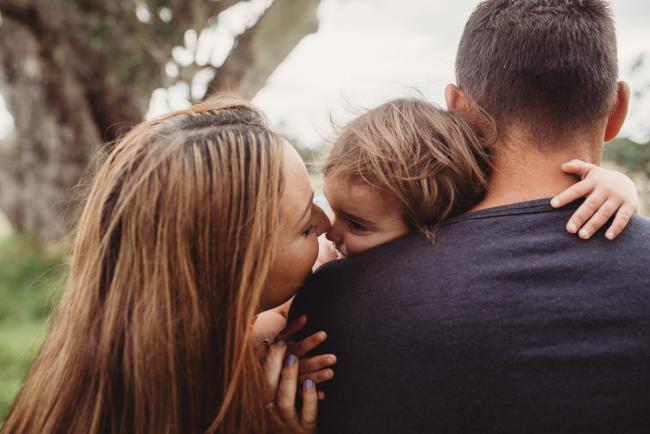 Mother giving nose kisses to her daughter who is cuddling her father with Perth family photographer at Perry's Paddock