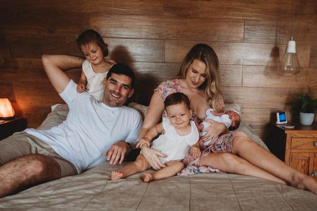 Family of 5 sitting on a bed during an in-home Perth newborn lifestyle session