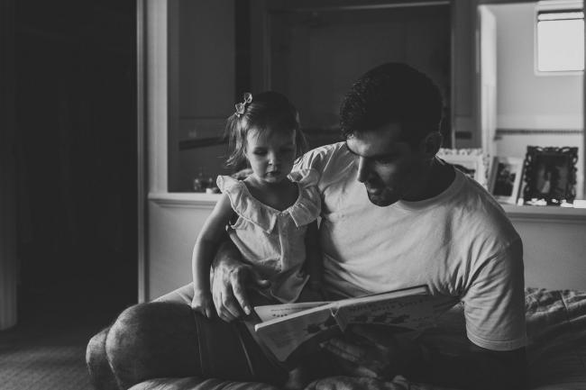 Black and white image of father reading a story to his daughter with Perth lifestyle family photographer