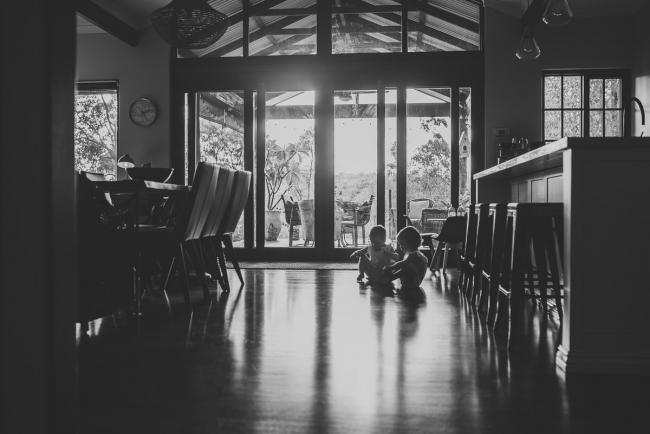 Black and white image of little girls sitting on the floor in front of a window with Perth lifestyle family photographer