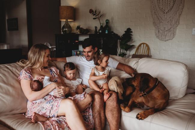 Family of 5 sitting on the couch with their large brown dog during an in-home Perth newborn lifestyle session