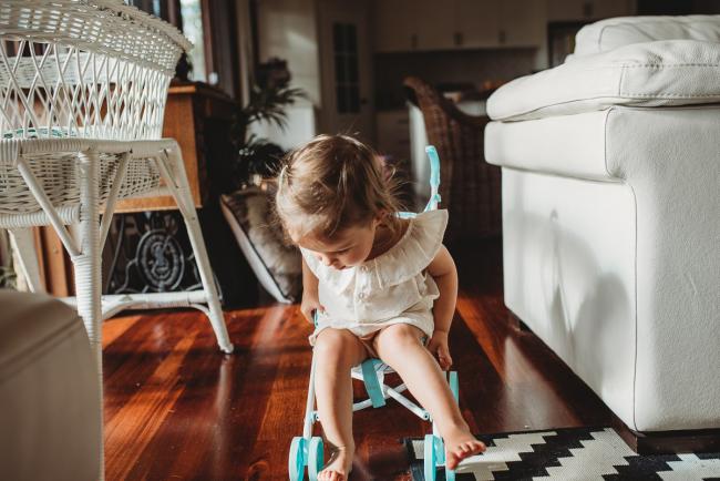 Little girl sitting in a toy stroller with Perth lifestyle family photographer