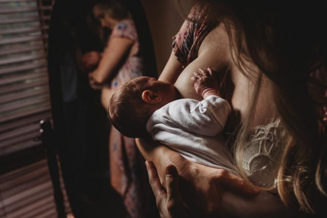 Mother breastfeeding her new baby during an in-home Perth newborn lifestyle session