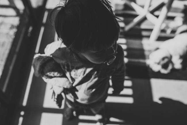 Black and white image of little boy standing in shadowed light with Perth lifestyle photographer
