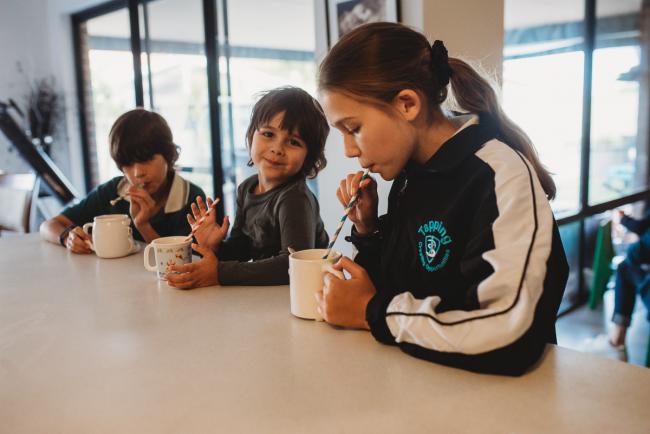 Three kids sitting at the kitchen bench drinking hot chocolates through straws with Perth family photographer