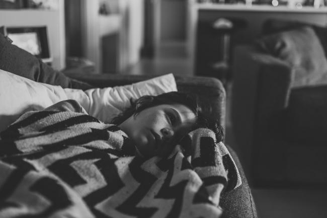 Black and white image of boy lying on the couch with blanket with Perth family lifestyle photographer