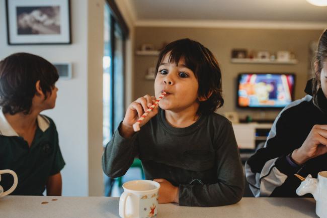 Little boy picking up a marshmallow with his straw with Perth family photographer