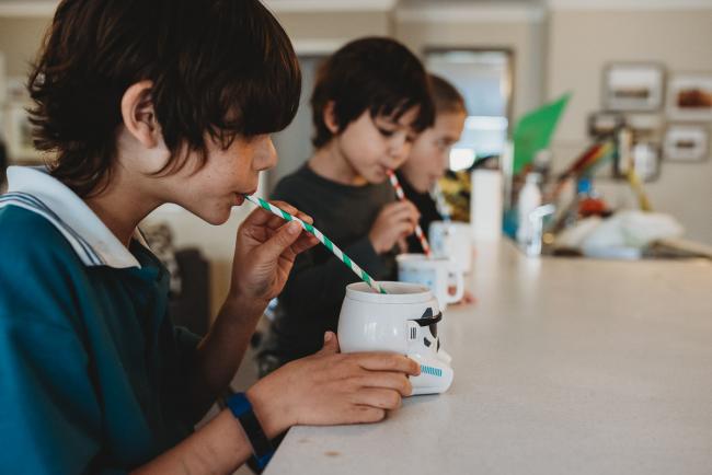 Three kids drinking hot chocolates through straws with Perth family photographer