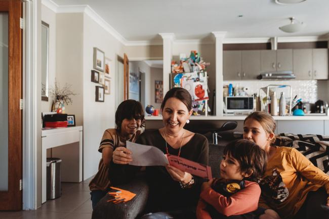 Mother reading a card as her three kids look on with Family Photographer Perth