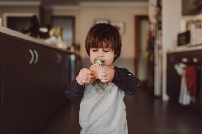 Little boy holding out his biscuit with Family photographer Perth