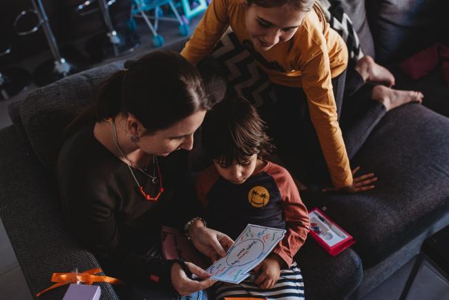Top down image of mother looking at a card with two kids with Family Photographer Perth
