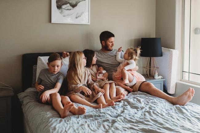 Father sitting on the bed with his 5 children during a Newborn lifestyle photographer Perth session