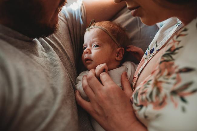 New baby laying between mother and father during a Newborn lifestyle photographer Perth session