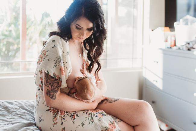 Mother sitting on the bed breastfeeding during a Perth Newborn photography session
