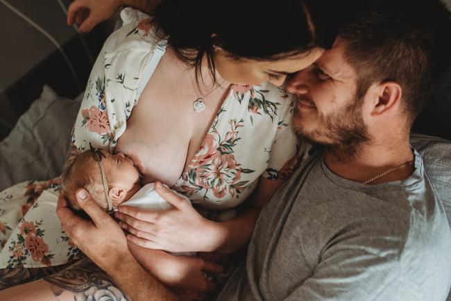 Mother breastfeeding as her and her husband touch foreheads during a Perth Newborn photography session