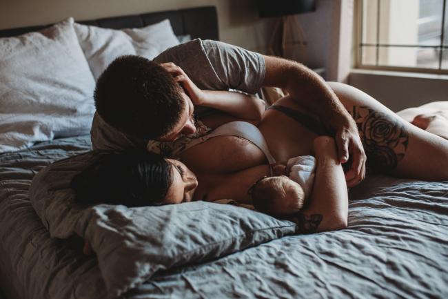 Parents laying on the bed with their new baby during a Perth Newborn photography session