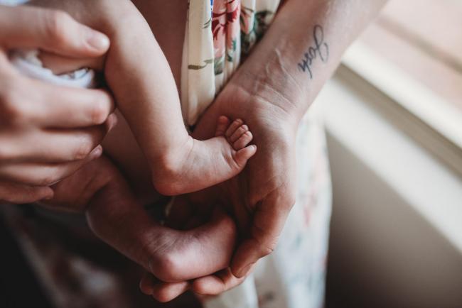 Mother holding her new baby's feet in her hands during a Newborn lifestyle photographer Perth session