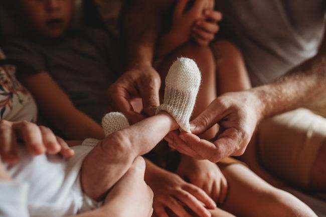 Father putting a bootie on his new baby during a Newborn lifestyle photographer Perth session