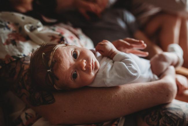Baby looking back at the camera while in her mother's arms during a Perth Newborn photography session