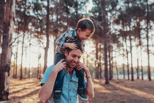 Little boy sitting on his dad's shoulders during a Perth maternity photography session at The Pines at golden hour