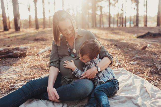 Little boy cuddling his mother's pregnant tummy during a Perth maternity session at The Pines during Golden Hour