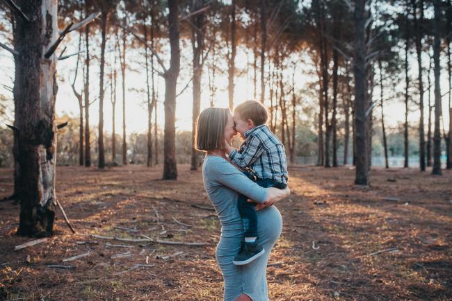 Mother holding son on top of her baby belly during a Perth maternity session at The Pines during Golden Hour
