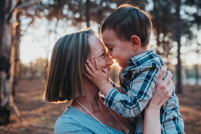 Son holding his mother's face during a Perth maternity photography session at The Pines at golden hour