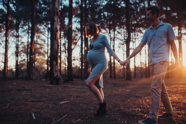 Pregnant couple walking during a Perth maternity photography session at The Pines at golden hour