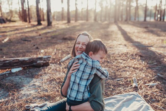 Little boy hugging his mother who is laughing during a Perth maternity photography session at The Pines at golden hour