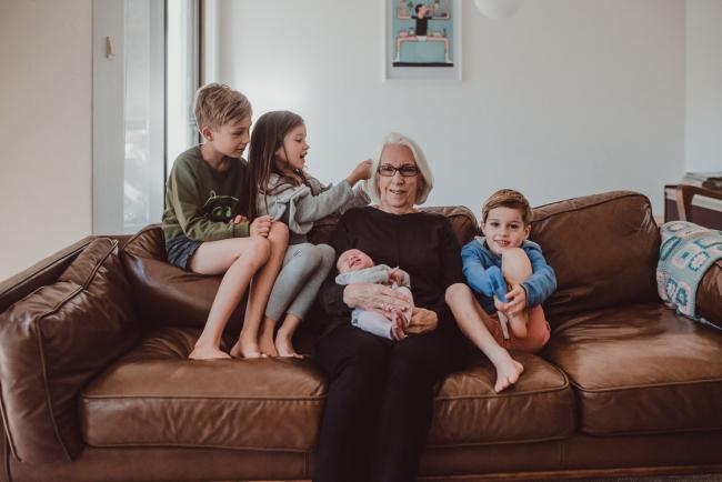 Newborn-Lifestyle-Photographer-Perth-15-of-54 Grandmother holding her new granddaughter with her other 3 grandkids around her during a lifestyle newborn photography session in Perth