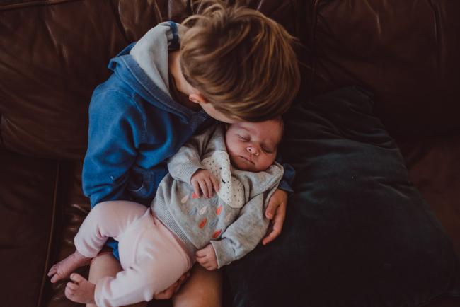 Newborn-Lifestyle-Photographer-Perth-27-of-54 Top down image of little boy kissing his baby sister during a lifestyle newborn photography session in Perth