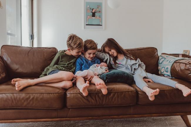 Three siblings looking at their new baby sister during a Newborn Lifestyle photography session in Perth