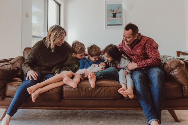 Family sitting on the couch and looking at their new baby during a Newborn Lifestyle photography session in Perth