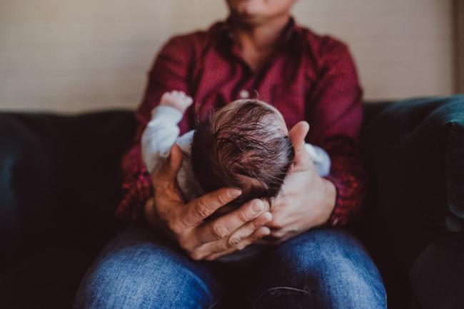 Newborn-Lifestyle-Photographer-Perth-38-of-54 Father holding his new baby sister's head in his hands during a lifestyle newborn photography session in Perth