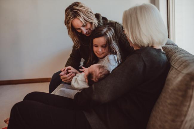 Newborn-Lifestyle-Photographer-Perth-53-of-54 Grandmother holding her granddaughter as mother and daughter look on during a lifestyle newborn photography session in Perth