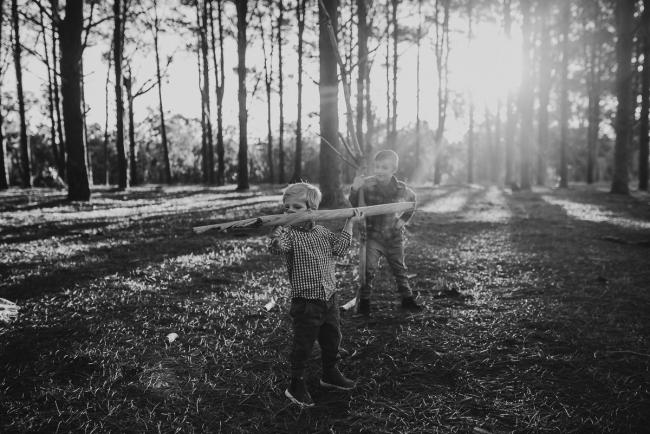The-Pines-Family-Photographer-Perth-14-of-60 Black and white image of brothers playing with sticks during a Perth Family Photography session during Golden Hour at The Pines