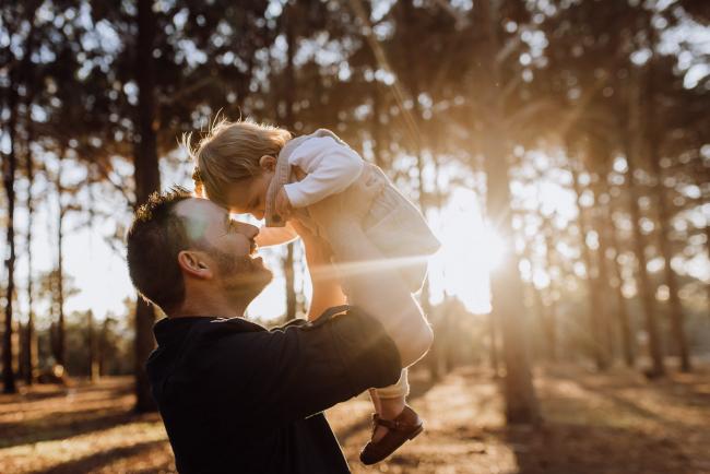 Father lifting his daughter into the air during a family photography Perth session at The Pines during golden hour