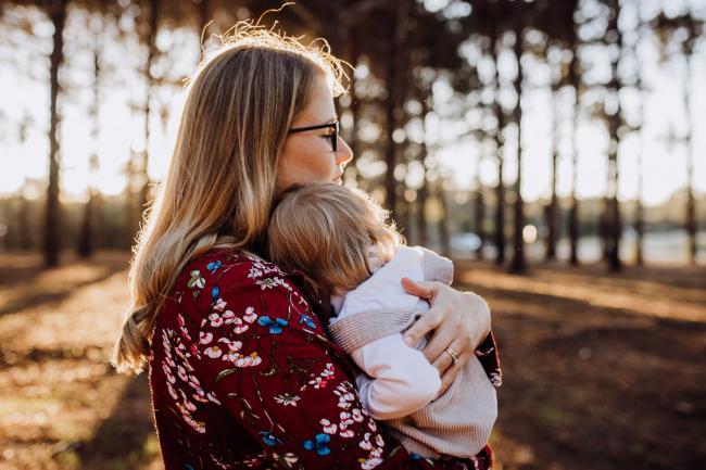 Little girl cuddling into her mother during a family photography Perth session at The Pines during golden hour