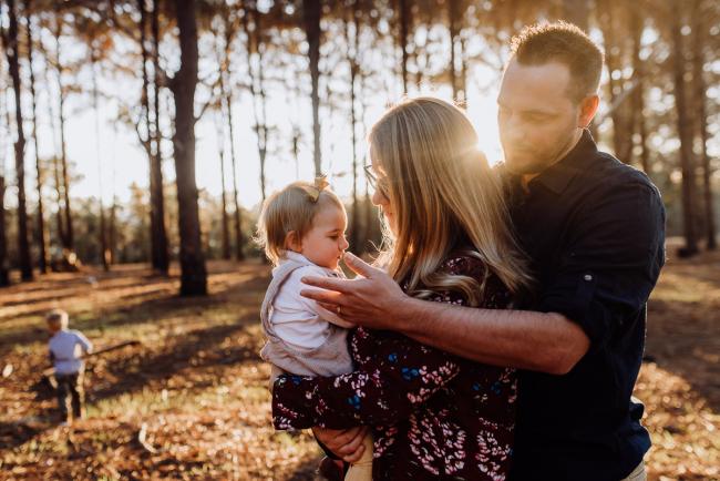 The-Pines-Family-Photographer-Perth-31-of-60 Parents holding their daughter during a Perth Family Photography session during Golden Hour at The Pines