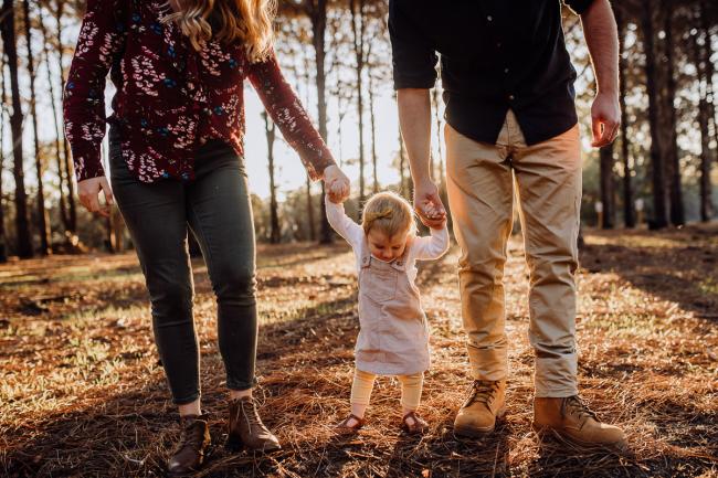 The-Pines-Family-Photographer-Perth-32-of-60 Parents holding hands with their daughter during a Perth Family Photography session during Golden Hour at The Pines