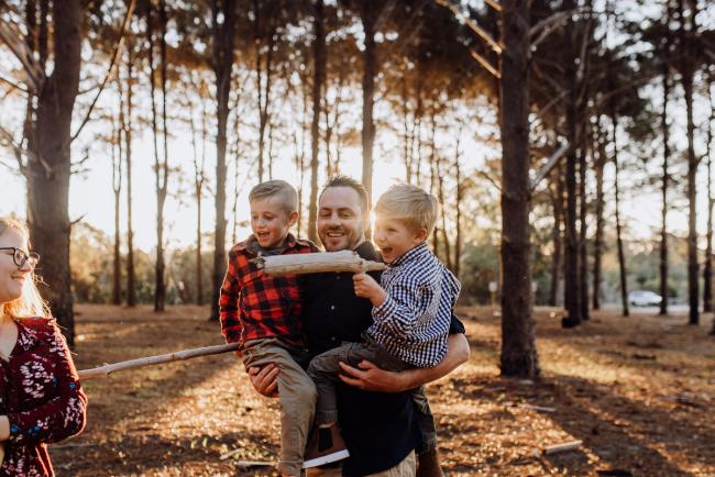 The-Pines-Family-Photographer-Perth-35-of-60 Father holding his boys as they play with sticks during a Perth Family Photography session during Golden Hour at The Pines