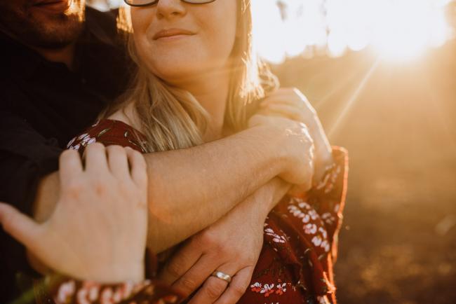 Close up of husband's arms wrapped around his wife's neck during a couple photography session in Perth during Golden hour at The Pines