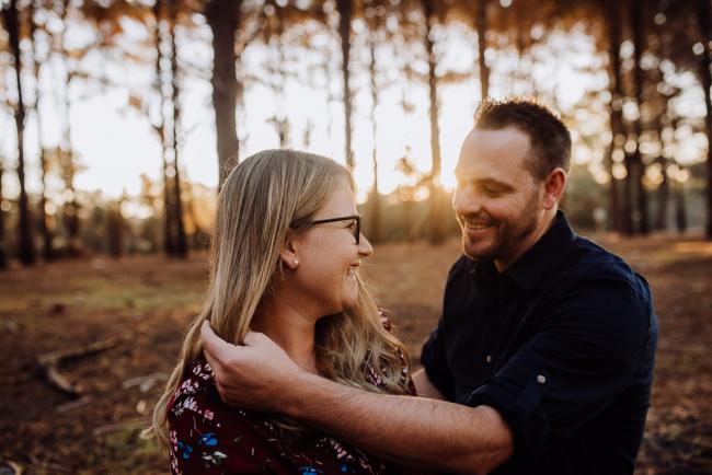 The-Pines-Family-Photographer-Perth-43-of-60 Husband playing with his wife's hair as they laugh during a Perth Family Photography session during Golden Hour at The Pines