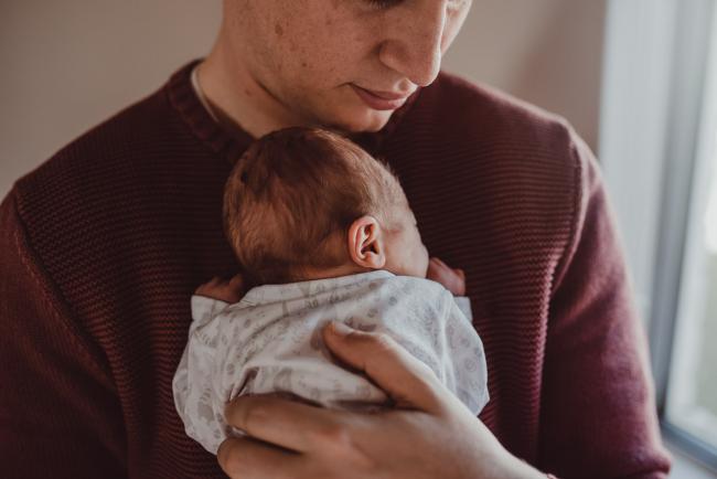Father holding his new baby to his chest during a Perth Fresh 48 photography session captured in home