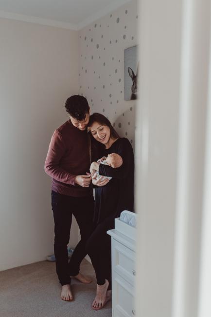 Looking through the doorway as parents stand in the nursery with their new baby during a Perth Fresh 48 photography session captured in home