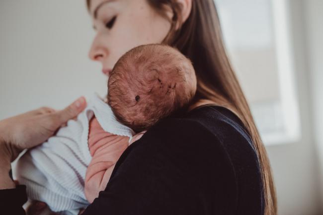 Baby head and wrinkly arms against mother's chest during a Perth Fresh 48 photography session captured in home